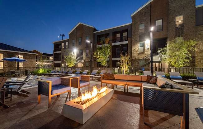 Outdoor Fire Pit Area with Lounge Furniture and View of Pool at Alta 3Eighty Apartments located in Aubrey, TX.