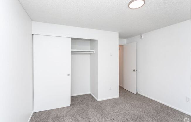 Carpeted bedroom with white walls, looking at the large closet with double sliding doors and shelf storage. at Talavera, Boise, 83705