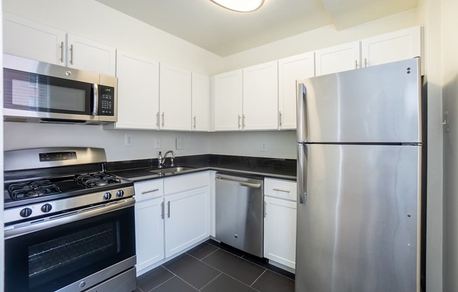 A modern kitchen with a stainless steel refrigerator, microwave, and oven.