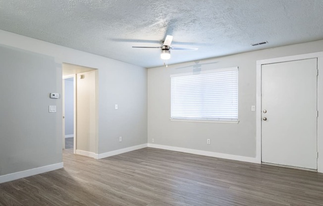 A room with a ceiling fan and wooden flooring.