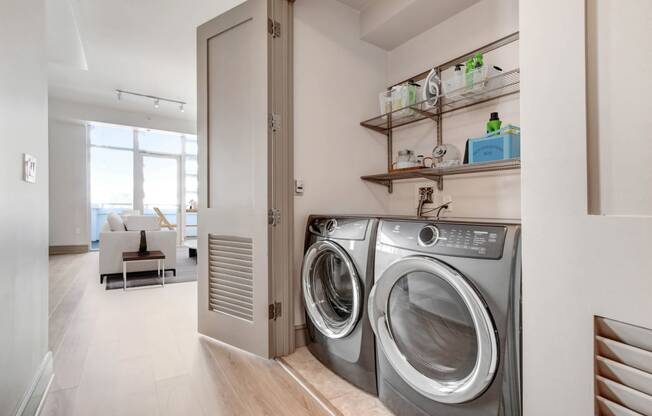 a washer and dryer in a living room with a door to a laundry