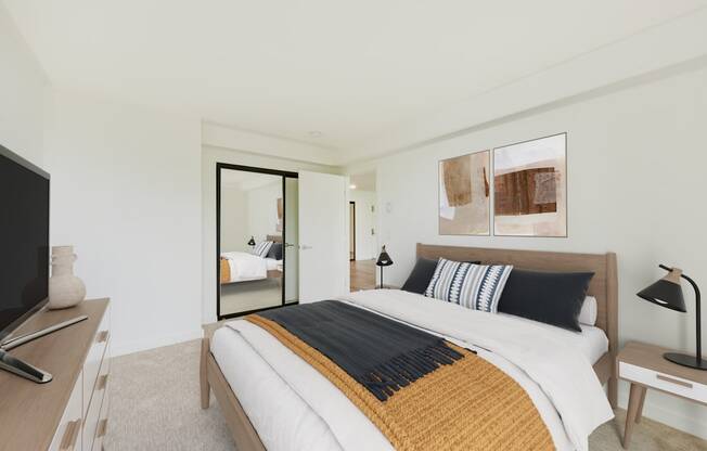 A bedroom with a bed, nightstand, and television.