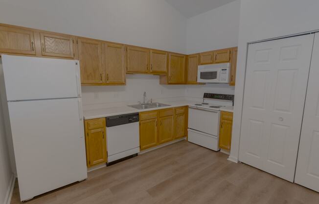 an empty kitchen with white appliances and wooden cabinets