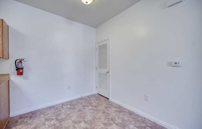 a bedroom with white walls and a white door with a fire extinguisher on the wall
