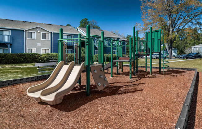 A playground with a green swing set and a slide.