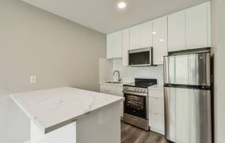 a white kitchen with stainless steel appliances and a marble counter top