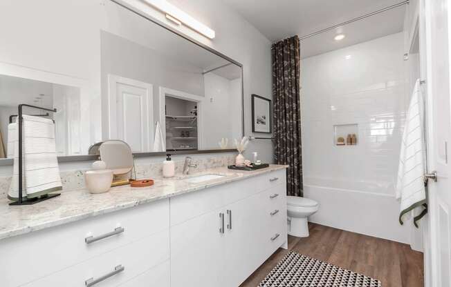 a white bathroom with a large mirror and a toilet