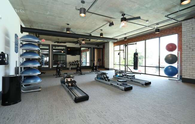 a workout room with treadmills and weights on the floor and a large window