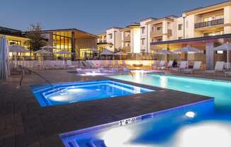 a swimming pool at night at an apartment complex with a hot tub