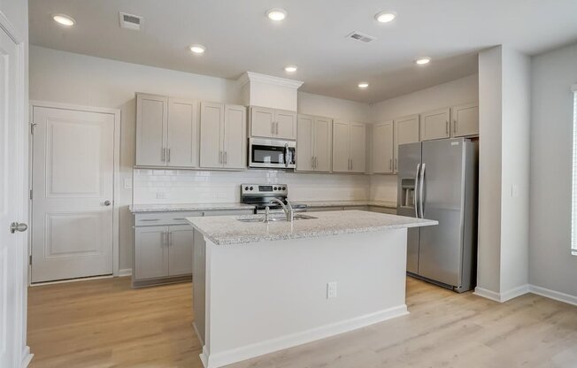 A kitchen with white cabinets and a marble island.