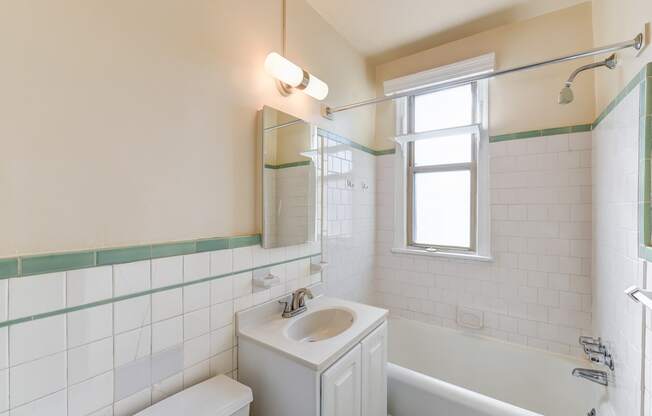 bathroom with toilet, vanity, tub, and window at eddystone apartments in washington dc