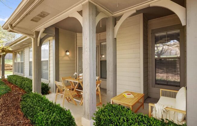 a covered porch with a table and chairs