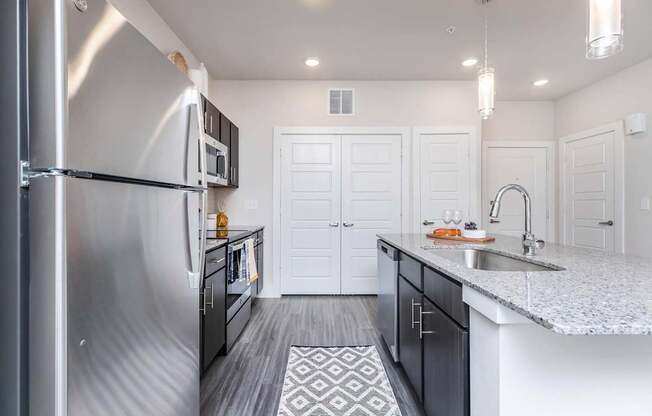 A modern kitchen with a stainless steel refrigerator and white cabinets.
