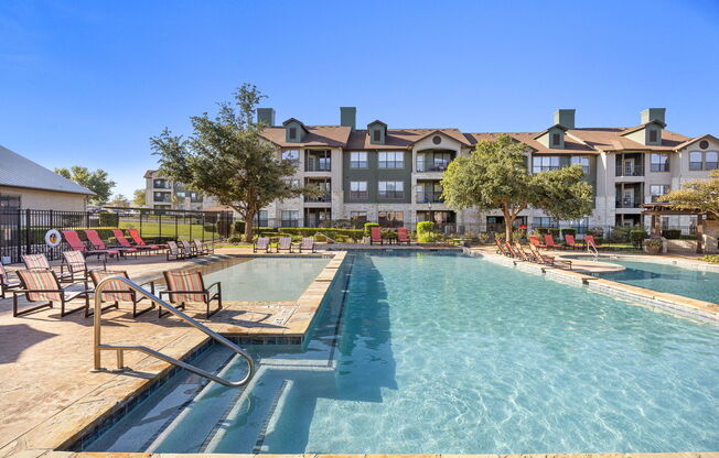 pool with chairs and apartment buildings at The Fairways at Star Ranch, Hutto, Texas