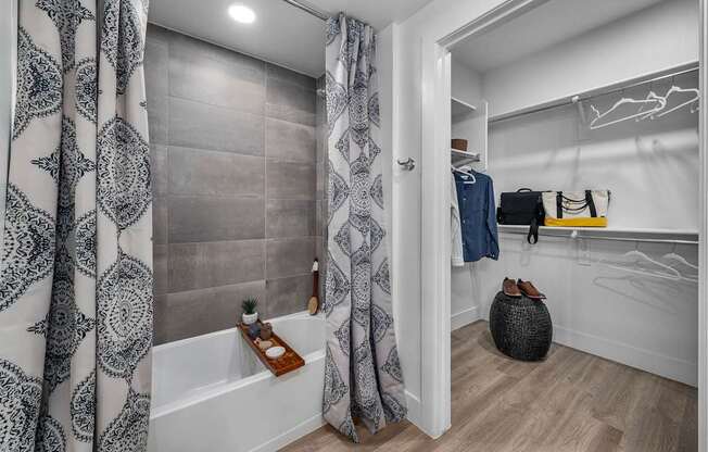 A bathroom with a white tub and a shower curtain with a grey pattern.