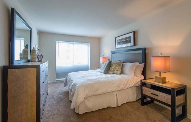 A bedroom with a bed, nightstand, and a dresser.