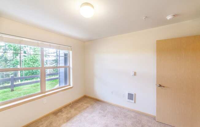 a bedroom with a large window and a wooden door