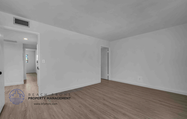 a bedroom with hardwood floors and white walls