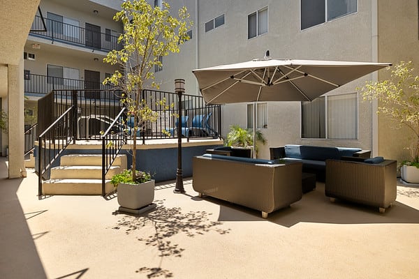 a patio with couches and an umbrella in an apartment buildingat NOHO GALLERY Apartments, California