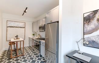 kitchen with white cabinetry, stainless steel appliances, microwave and kitchen island at the dahlia apartments in washington dc