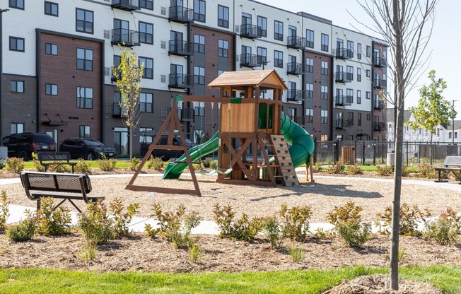 A playground with a green slide and a wooden structure.