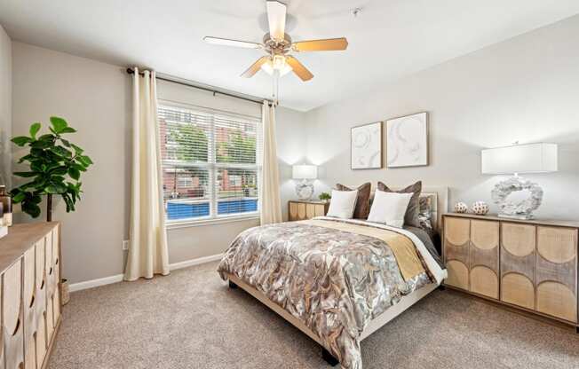 Bright bedroom with ceiling fan and large window at The Grand at Upper Kirby apartments in Houston, TX