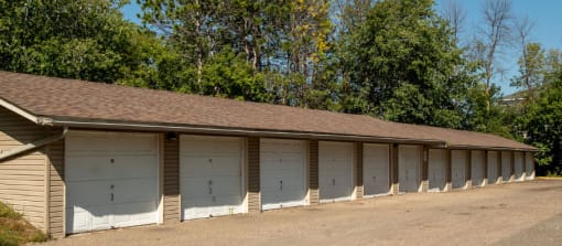 a row of garages with white doors and brown roofs