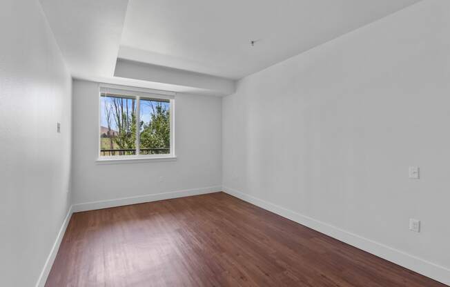 a bedroom with hardwood floors and a large window