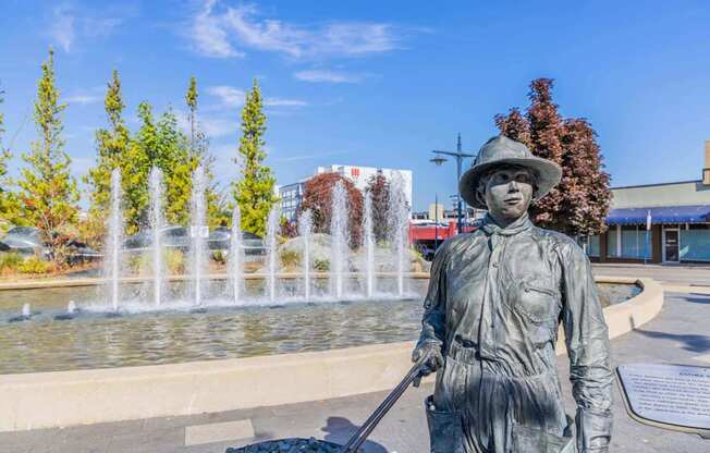 A statue of a person holding a shovel stands in front of a fountain at Spyglass Hill Apartments, Bremerton, 98337