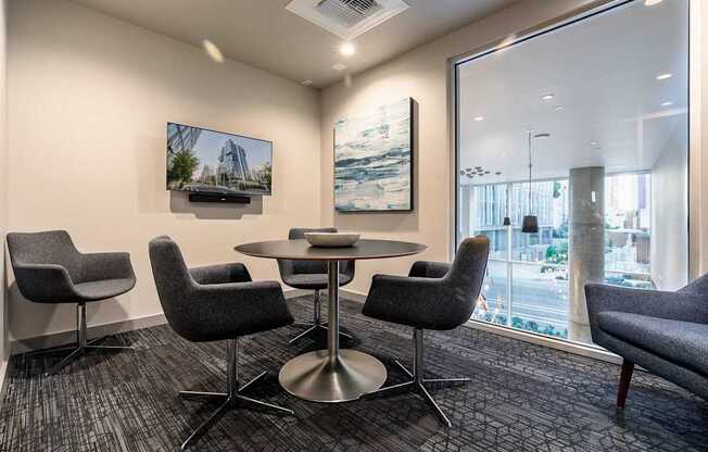A conference room with a table surrounded by chairs and a television on the wall.