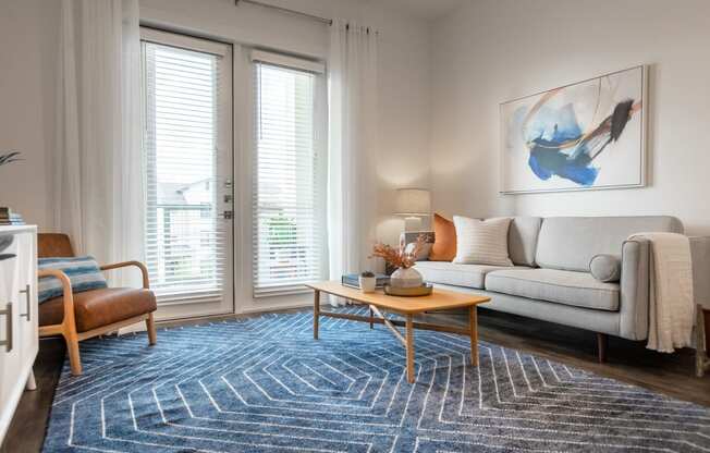 a living room with large windows and a blue rug