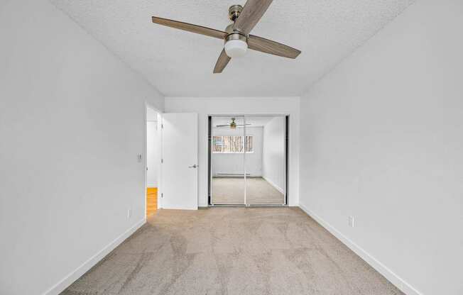 a bedroom with a ceiling fan and a door to a hallway