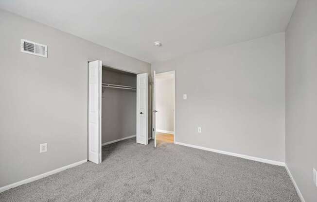 a bedroom with carpet and an open door to a closet at ReNew Odenton