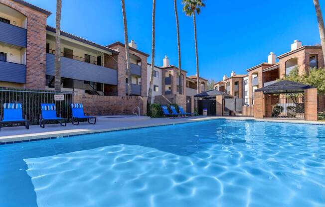 A swimming pool surrounded by palm trees and apartment buildings.