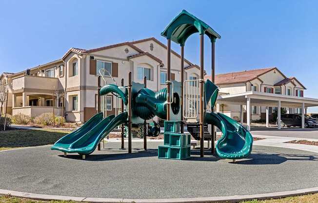 A playground with a green slide and a green canopy.