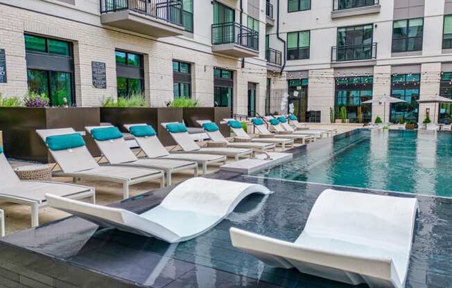 a pool with lounge chairs and a building in the background