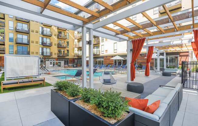 a communal area with couches and plants in front of an apartment building
