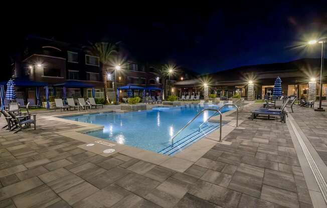 A swimming pool area at night with lights on.