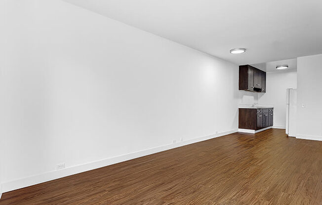 an empty living room with a kitchen in the background