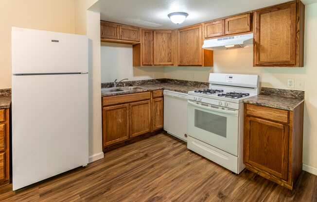 an empty kitchen with white appliances and wooden cabinets