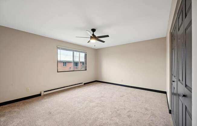 an empty living room with a ceiling fan and a window