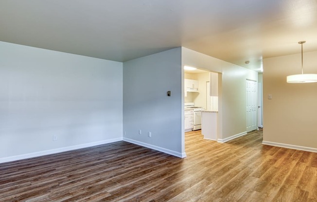 an empty living room with wood flooring and a renovated kitchen at Gates of West Bay in Norfolk, 23503