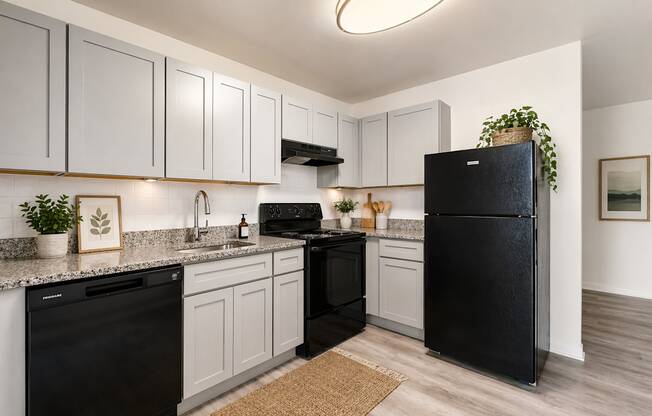 A black refrigerator stands in a kitchen with white cabinets and a black dishwasher.