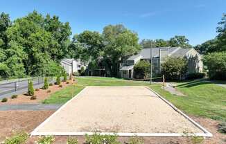 A sand volleyball court is surrounded by trees and houses.