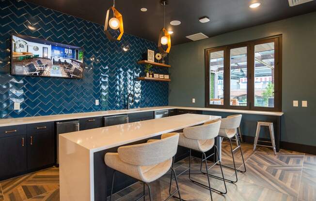 a kitchen with a long counter and chairs and a tv on the wall