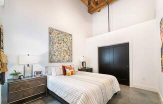 A bedroom with a large bed and a painting on the wall.