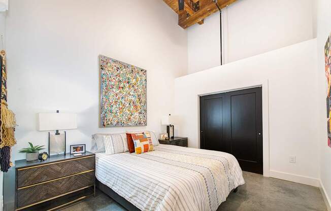 A bedroom with a large bed and a painting on the wall.