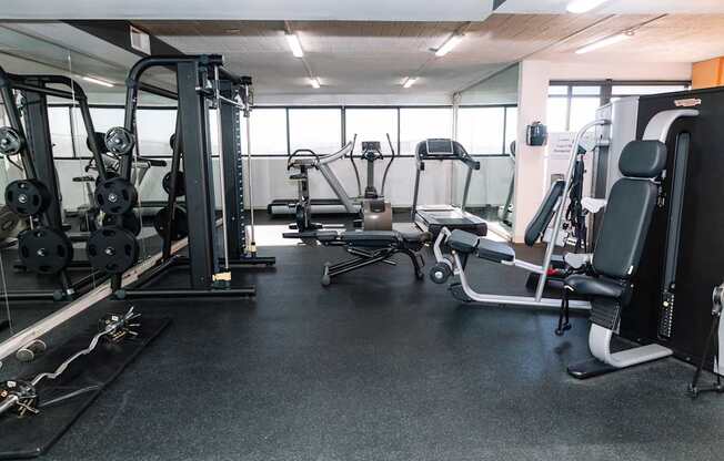 A gym with a variety of equipment including a leg press machine, a chest press machine, and a rowing machine.