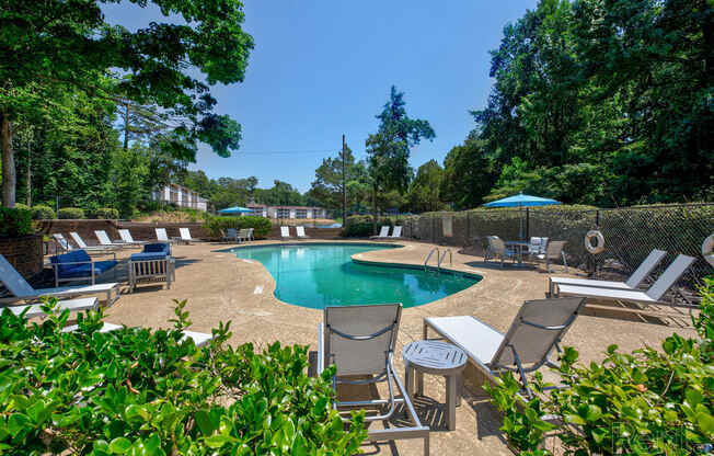 the pool is surrounded by chairs and umbrellas and trees