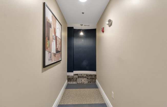 a long hallway with a black accent wall and carpeted flooring and a staircase